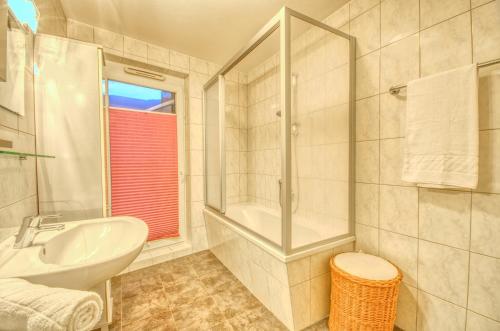 ein weißes Bad mit einem Waschbecken und einer Dusche in der Unterkunft Penthouse Ari - by Alpen Apartments in Zell am See