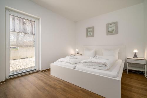 Un dormitorio blanco con una cama blanca y una ventana. en Ferienhaus Schilfblick, en Buchholz