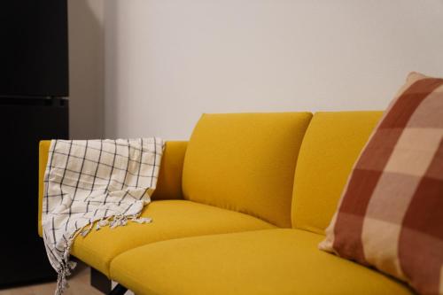 Żółta kanapa z poduszką w kratę w obiekcie Penthouse 1-bedroom flat in Hiroo Shibuya w Tokio