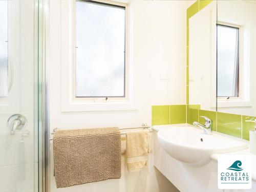 a white bathroom with a sink and a mirror at Woodland Retreat - Phillip Island - Ramada Resort in Cowes