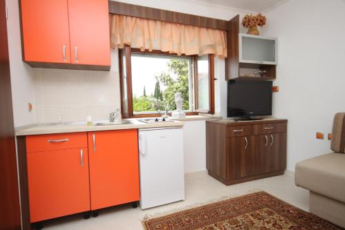 a kitchen with orange cabinets and a television in it at Apartments with a parking space Mocici, Dubrovnik - 9081 in Mlini