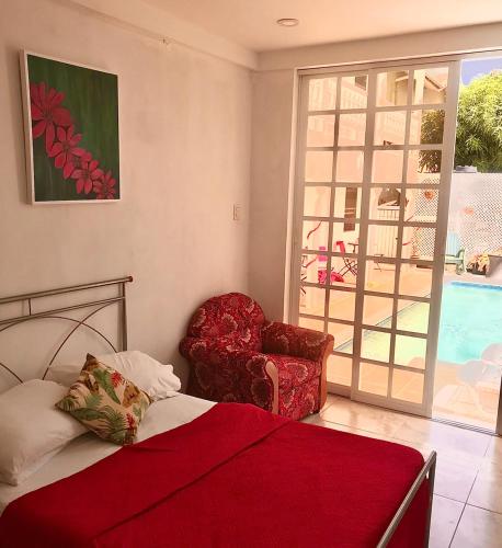 a bedroom with a bed and a chair and a window at The PoolSide Pad- 5 mins from Airport & Beaches in Bon Accord