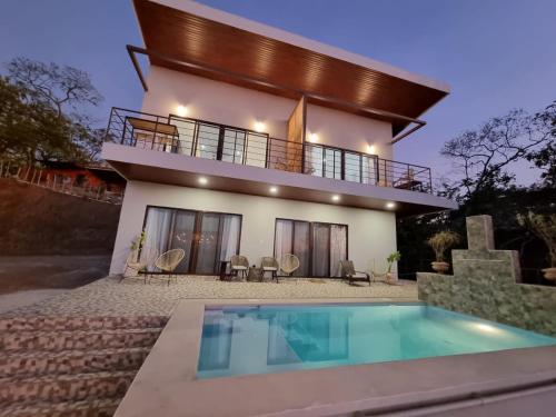 a house with a swimming pool in front of it at Pinilla Highlands Incredible Mountain Ocean views in Tamarindo