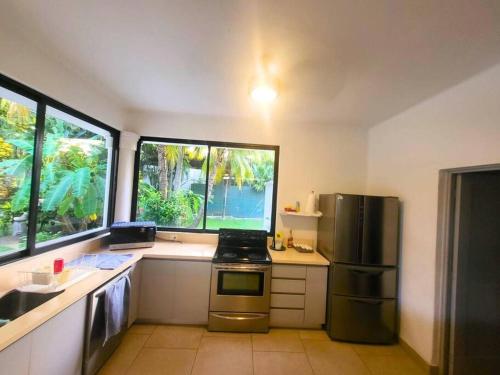 a kitchen with a stainless steel refrigerator and two windows at Casa Don Willo in Escuintla