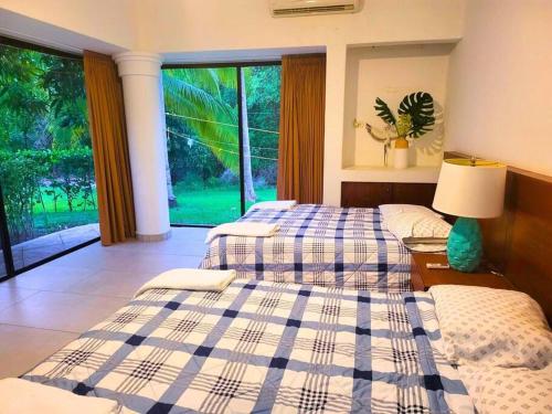 a bedroom with two beds and a large window at Casa Don Willo in Escuintla