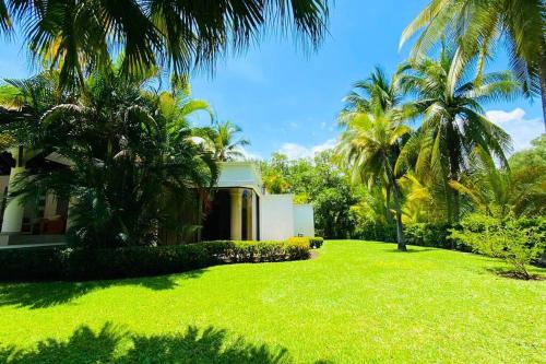 a green yard with palm trees in front of a house at Casa Don Willo in Escuintla