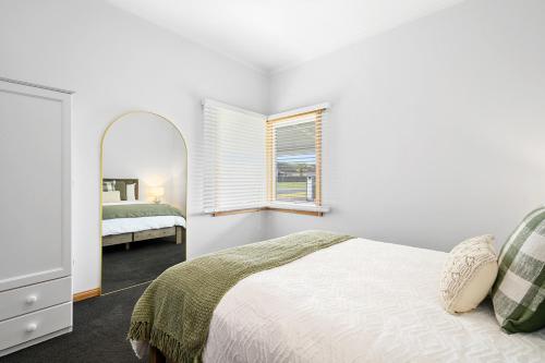 a white bedroom with a bed and a mirror at LuCo House Stanley in Stanley