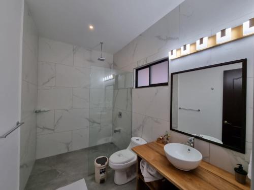 a bathroom with a sink and a toilet and a mirror at Pinilla Highlands Incredible mountain views in Tamarindo