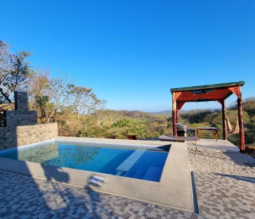 a swimming pool with a gazebo and a table at Pinilla Highlands Incredible mountain views in Tamarindo