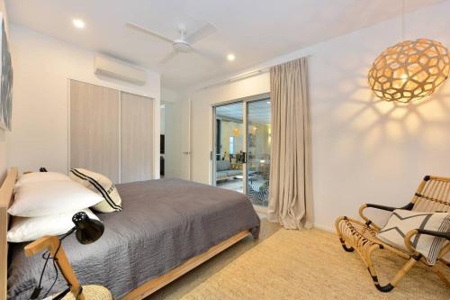 een slaapkamer met een bed, een stoel en een raam bij Tropical Villa on Craven Close in Port Douglas
