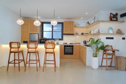 a kitchen with wooden cabinets and bar stools at Admire Villa - a luxury private villa with Pool in Legian