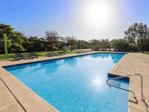 a large blue swimming pool with chairs in a park at Woodland Retreat - Phillip Island in Cowes