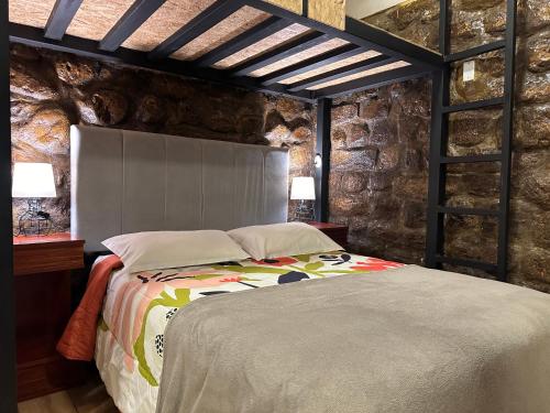 a bedroom with a bed in a stone wall at Blacky Hostel and Apartments in Cusco