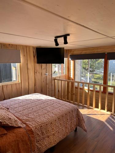 a bedroom with a bed and a flat screen tv at Cabaña Loft del Sur Premium in Chonchi