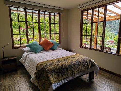 a bedroom with a bed with pillows and two windows at Casa de Campo Don Panchito 
