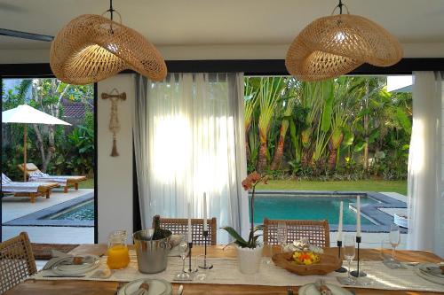 a dining room table with a view of a pool at Admire Villa - a luxury private villa with Pool in Legian