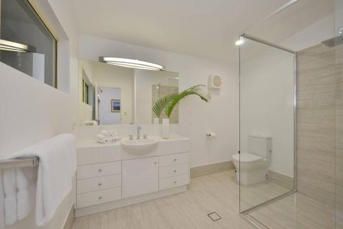 y baño blanco con lavabo y ducha. en Villa Solina, en Port Douglas