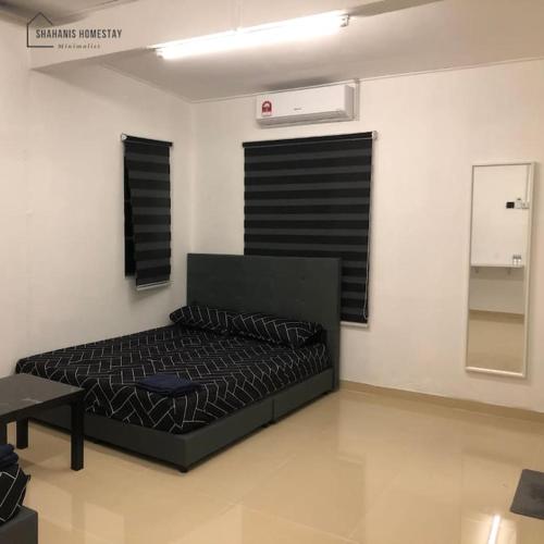 a bedroom with a black bed in a room at Shahanis Homestay. A hotel-like stay experience! in Kijal