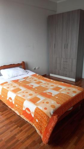 AyacuchoDepa في اياكوتشو: سرير مع لحاف برتقالي وبيض في غرفة النوم