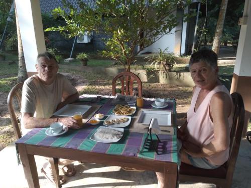 two people sitting at a table with food on it at Elegant Hamlets Home Stay in Chilaw