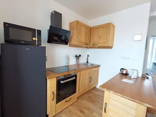 une cuisine avec un réfrigérateur noir et des armoires en bois dans l'établissement Appartement rénové au centre de Trébeurden, 400m de la plage, proche commerces - FR-1-368-407, à Trébeurden