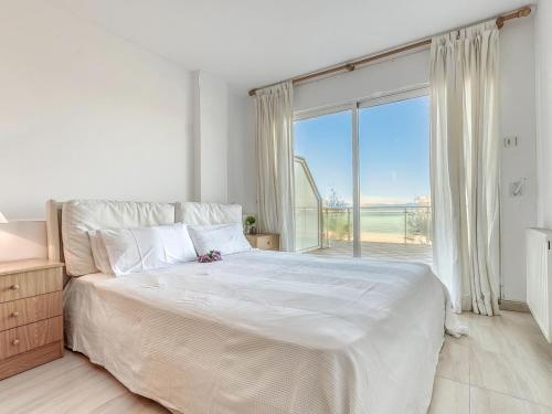 um quarto branco com uma cama grande e uma janela grande em Apartamento L'Escala, 2 dormitorios, 6 personas - ES-89-130 em Torroella de Montgrí
