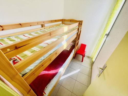 Ce lit se trouve dans un dortoir doté de 2 lits superposés et d'une chaise rouge. dans l'établissement Studio rénové, 4 pers, parking privé, proche port et plage - Cap d'Agde - FR-1-723-127, au Cap d'Agde