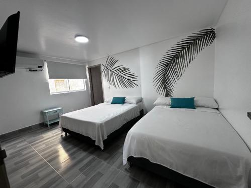 1 dormitorio con 2 camas y una hoja de palmera en Vista increíble Chirama Rodadero, en Santa Marta