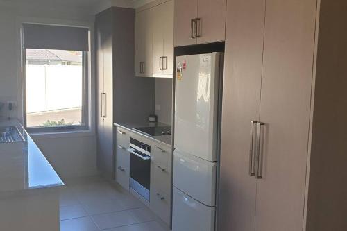 a kitchen with white cabinets and a white refrigerator at Shore beats working in Port Sorell