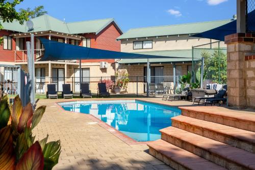 a swimming pool in front of a house at Amalfi Resort Busselton's Best Kept Secret in Busselton