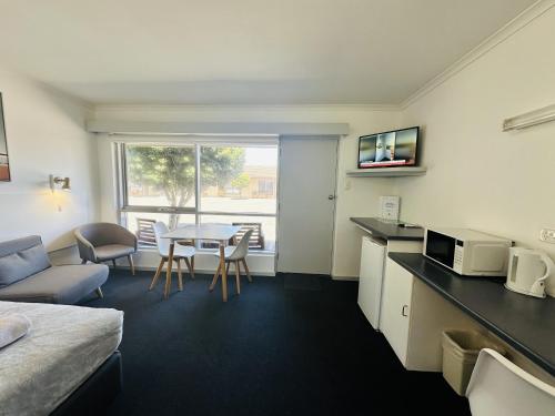 a hotel room with a bed and a kitchen and a table at Beachport Motor Inn in Beachport