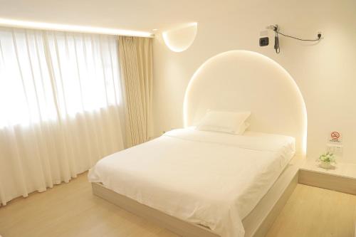 a white bedroom with an oval bed in a room at 三亚豪晟珠崖民宿(海棠湾免税城店) in Sanya