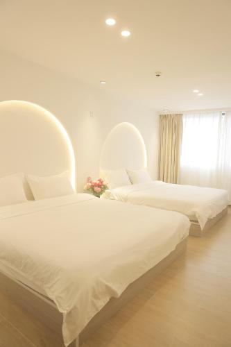 a bedroom with two beds with white sheets and a window at 三亚豪晟珠崖民宿(海棠湾免税城店) in Sanya