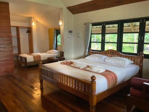 een slaapkamer met 2 bedden en een groot raam bij The Chevalley Beach Resort in Satun