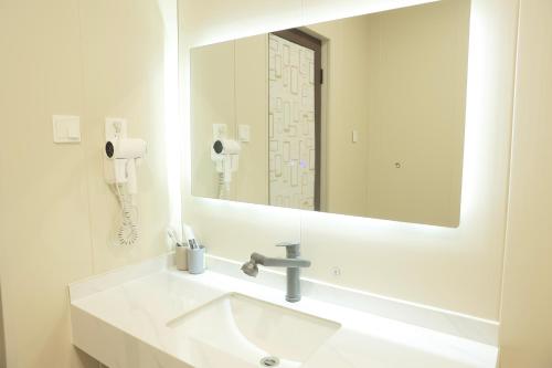 a bathroom with a sink with a mirror and a phone at 三亚豪晟珠崖民宿(海棠湾免税城店) in Sanya