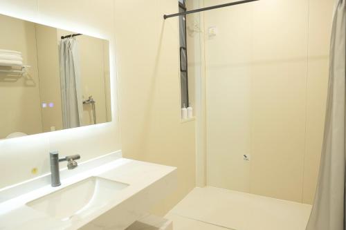 a white bathroom with a sink and a shower at 三亚豪晟珠崖民宿(海棠湾免税城店) in Sanya
