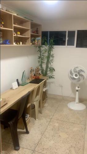 Habitación con escritorio, ventilador y planta. en Habitacion en casa familiar en Barranquilla