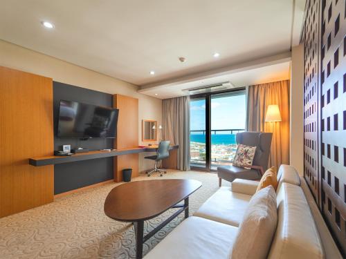 a living room with a couch and a tv at Ramada by Wyndham Jeju Hamdeok in Jeju