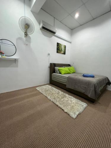 a bedroom with a bed with a green pillow and a rug at Homestay Seri Lanchang No16 in Kangar
