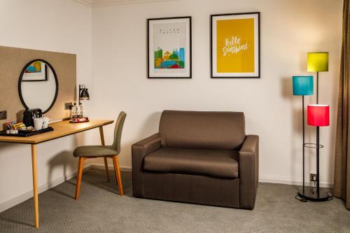a room with a chair and a desk and a mirror at Holiday Inn Milton Keynes Central by IHG in Milton Keynes
