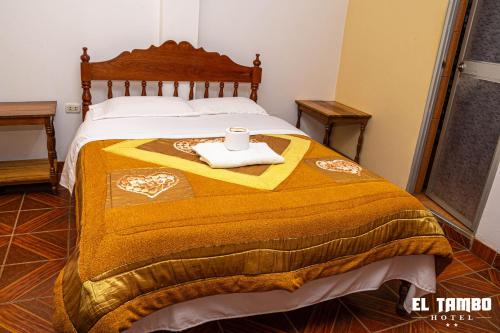 Una cama con una manta amarilla y una taza. en HOTEL EL TAMBO, en Chachapoyas