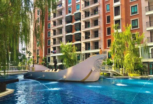 a slide in a pool in front of a building at Espana Resort Jomtien Beach Pattaya in Jomtien Beach