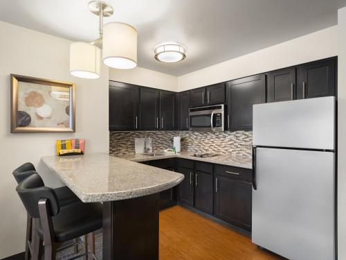 a kitchen with black cabinets and a white refrigerator at Staybridge Suites Midvale by IHG in Midvale