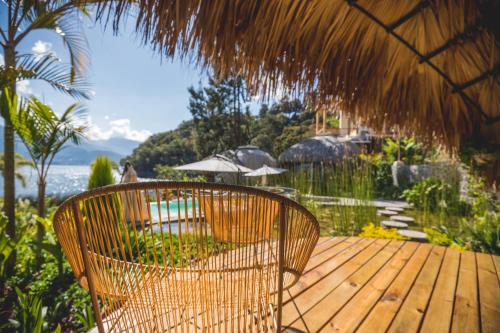 a wooden deck with a chair and an umbrella at Kula Maya Boutique Hotel and Spa in San Marcos La Laguna