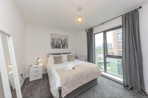 a bedroom with a bed and a large window at NovaNest Salford Apartment in Manchester