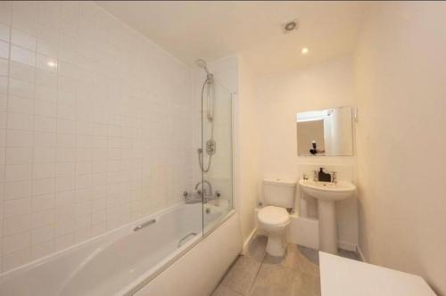 a white bathroom with a toilet and a sink at NovaNest Salford Apartment in Manchester