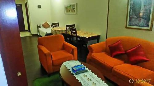 a living room with an orange couch and a table at Fantastic appartment at times square Kuala Lumpur in Kuala Lumpur
