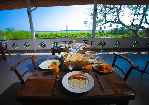a wooden table with plates of food on it at Birdsong Leisure Resort in Tissamaharama