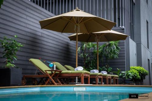 a group of chairs and umbrellas next to a pool at Sayarsan Hotel Yangon in Yangon