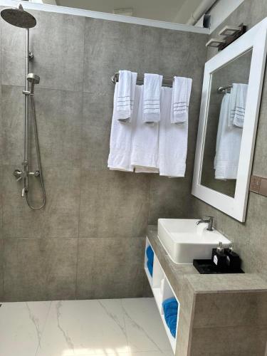 a bathroom with a sink and a shower with white towels at Island Luxury Dive Hotel - Fulhadhoo in Fulhadhoo